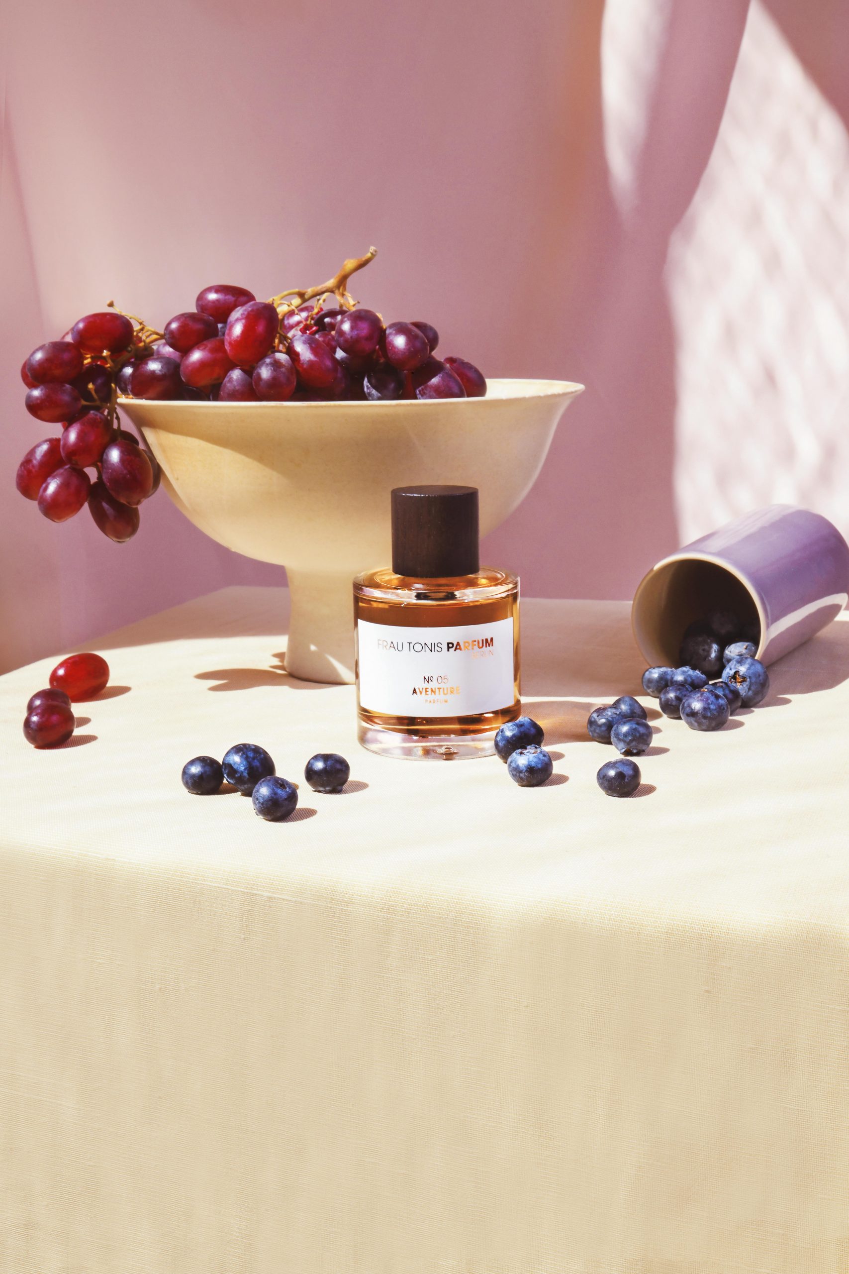 Artistic shot of Frau Tonis Parfum with grapes and blueberries on a Berlin table setting.