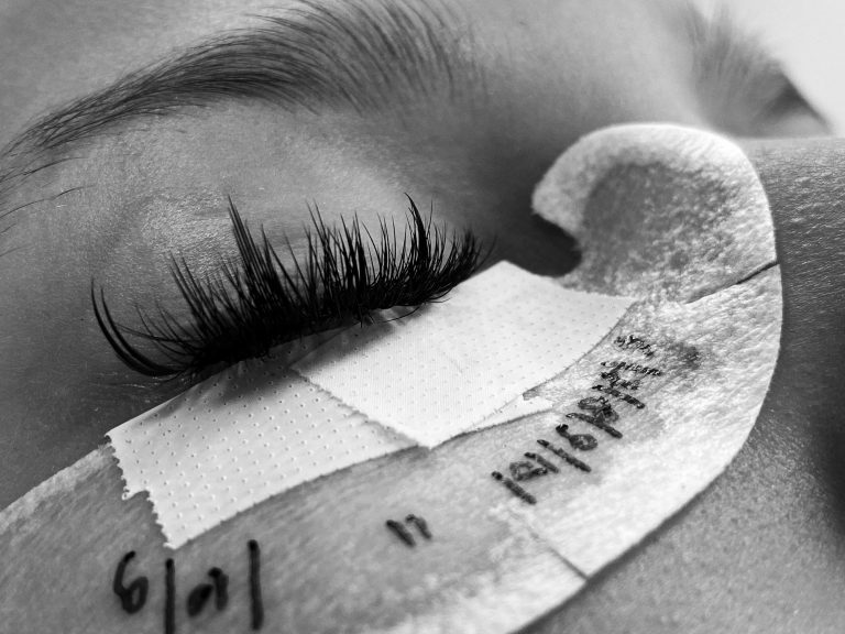 Detailed black and white image of eyelash extension procedure close-up.