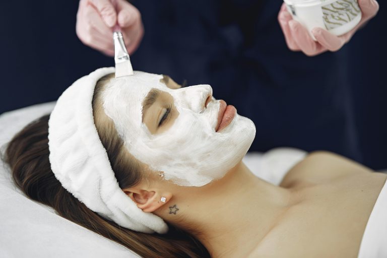 Close-up of a woman with eyes closed enjoying a calming facial mask application at a spa.