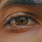 Detailed close-up of a honey-colored eye displaying natural eyelashes and skin texture.