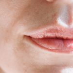 Intimate close-up of feminine lips with soft natural light highlighting the skin texture.